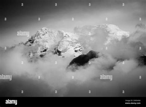 Grayscale Shot Of Mountains Covered In Snow And Clouds Stock Photo Alamy
