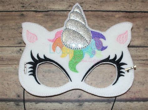 A White Mask With Silver Sequins And A Unicorns Horn On It