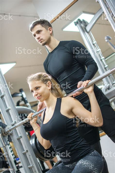 Young Sportswoman Lifting Weights With Assistance Of Her Personal