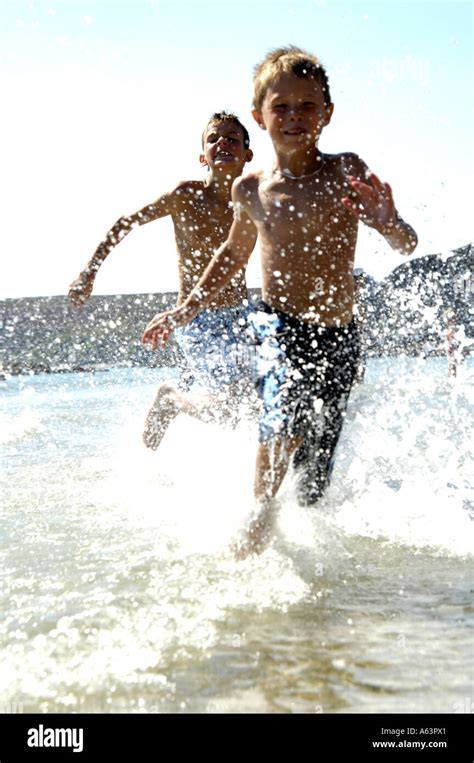 Two Boys Playing In Water On Beach Stock Photo Alamy