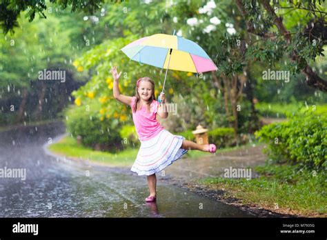 Kid Playing Out In The Rain Children With Umbrella Play Outdoors In