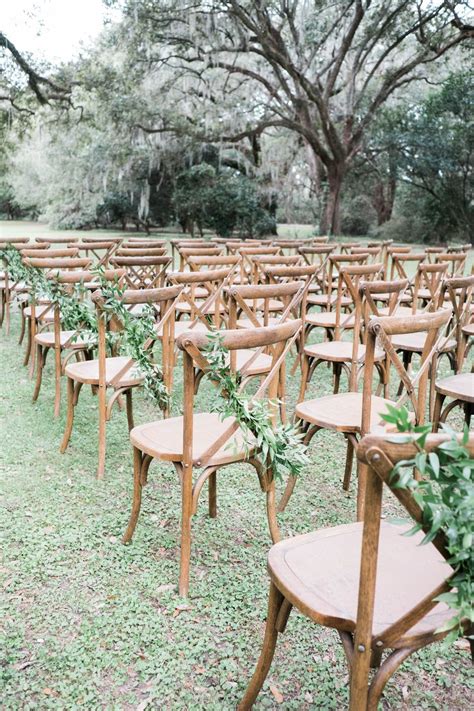 When renting chairs for a wedding, start searching for rental companies four to six months before the big day. Greenery adorned wedding ceremony chairs at an outdoor ...