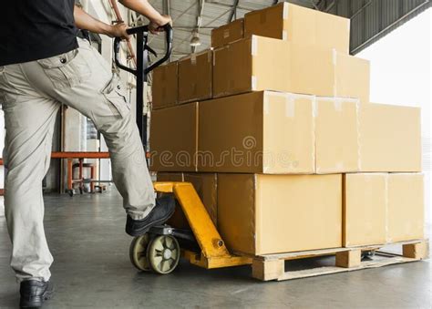 Warehouse Worker Working With Hand Pallet Truck Unloading Shipment Goods At Warehouse Stock