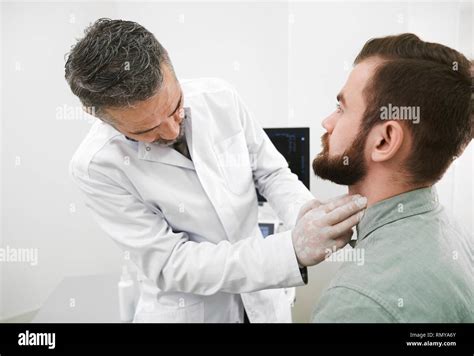 Doctor Palpating And Examining Lymph Nodes On Mans Neck Bearded