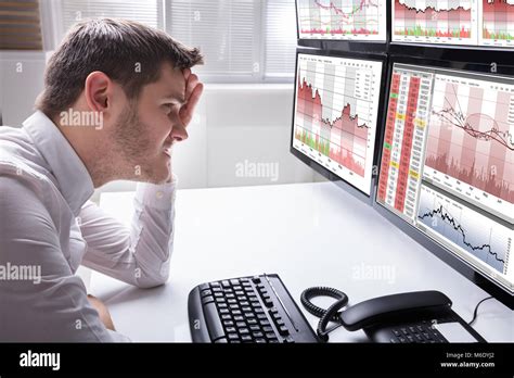 Side View Of A Sad Young Male Operator Looking At Graphs On Multiple