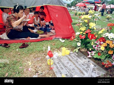 A Filipino Christian family eat their lunch beside the tombs of their