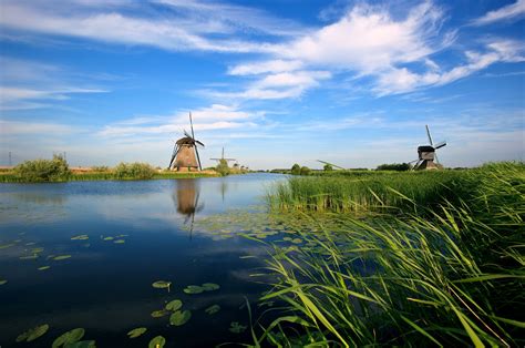 Brown Watermill Surrounded With Lake And Green Grass Under Blue And