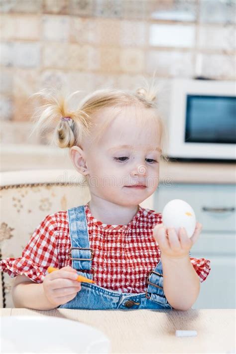 A Little Girl Sitting At A Table Painting Easter Egg Stock Image