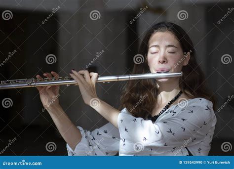 A Beautiful Woman Posing While Playing On A Flute Stock Photo Image
