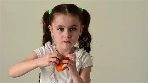 A Little Girl Peels An Orange On A White Background Stock Footage