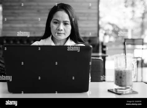 Mature Asian Businesswoman Using Laptop Computer In Coffee Shop Stock