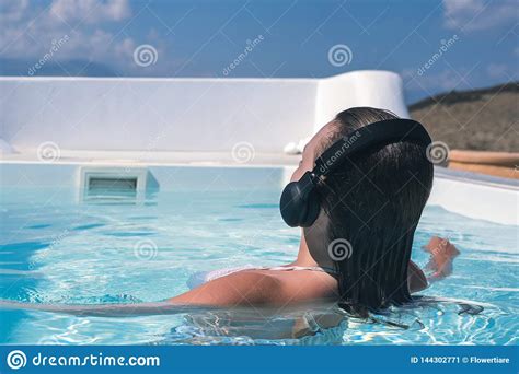 woman in the headphones listening to the music bathing in a pool stock image image of bikini