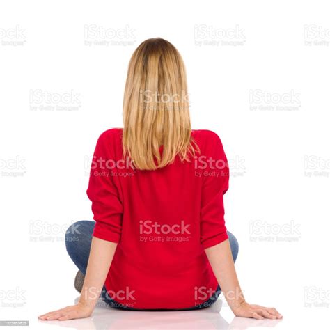 Young Woman In Red Sweater Is Sitting Legs Crossed On A Floor Rear View