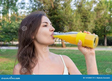 closeup of beautiful girl with a bottle of fresh juice healthy woman is posing with lemonade