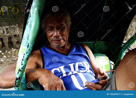 A Mature Filipino Man Sits On A Chair And Poses For The Camera