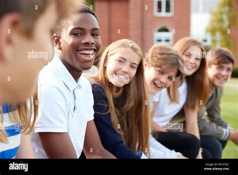 Group Of Teenage Students Sitting Outside School Buildings Stock Photo