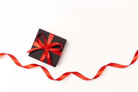 Flat Lay Of Black Present Box With Red Bow And Ribbon On The White