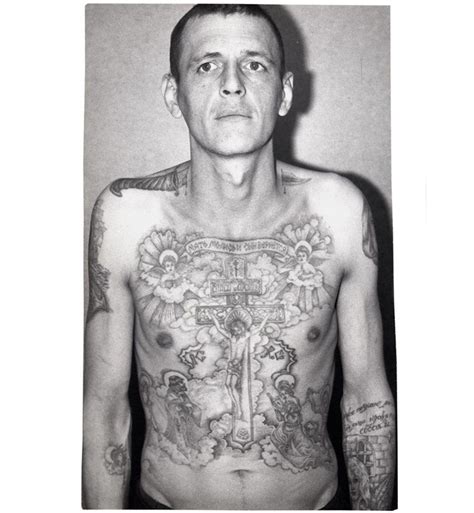 a man with tattoos on his chest standing in front of a wall