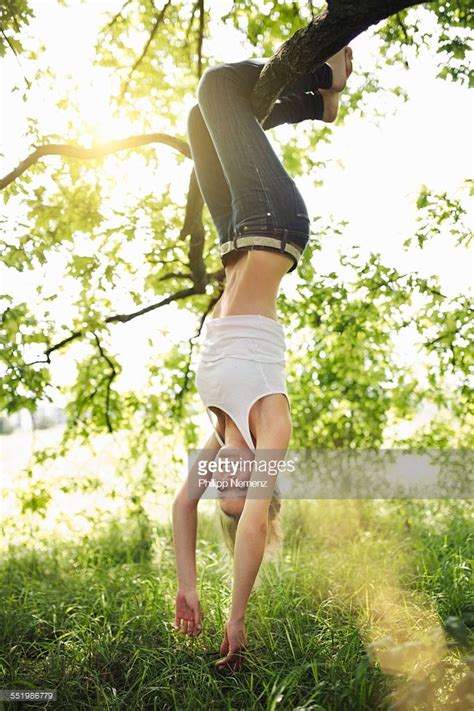 Young Woman Hanging Upside Down From Tree Branch Hanging Upside Down