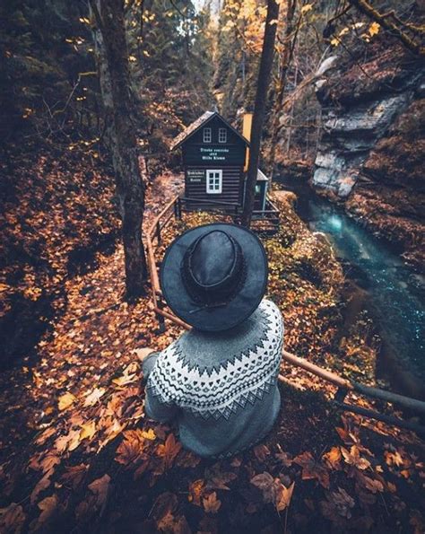 A Person With A Hat On Their Head Looking At A Cabin In The Woods Near