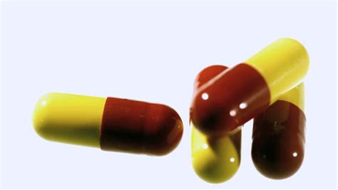 Red And Yellow Capsule Tablets Falling And Bouncing In Slow Motion