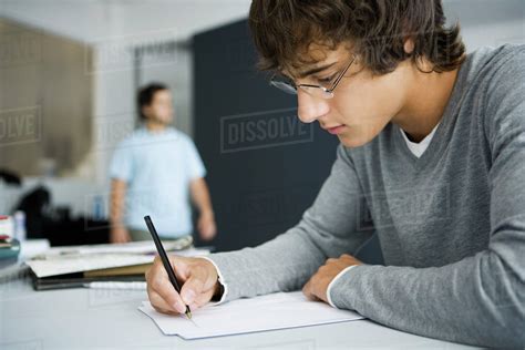 College Student Writing At Desk In Classroom Stock Photo Dissolve