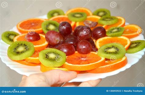 Fresh Sliced Fruits On A Plate In Hand White Background Stock Image