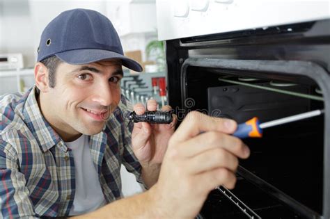 Repairman With Screwdriver Fixing Oven In Kitchen Stock Image Image