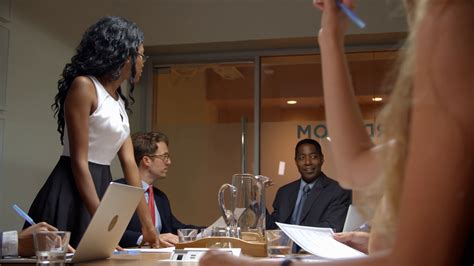 Young black woman stands to address team at business ...