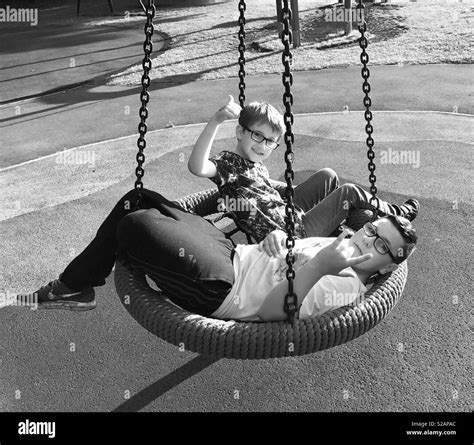 2 Children On A Playground Swing In Black And White Stock Photo Alamy