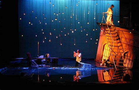 Two People Standing On Top Of A Stage In Front Of A Blue Curtain With