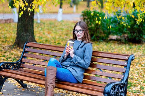 Beautiful Young Woman Sitting On A Bench Drinking Coffee Or Hot Tea In
