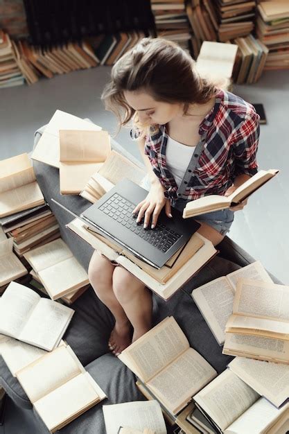 Free Photo | Young teenager girl using the laptop computer surrounded by many books.