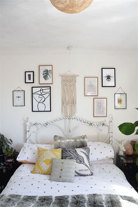 A White Bed Topped With Lots Of Pillows Next To Pictures On The Wall