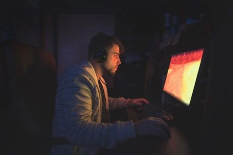 Милый мужчина геймер сидит в уютной комнате за компьютером и играет в