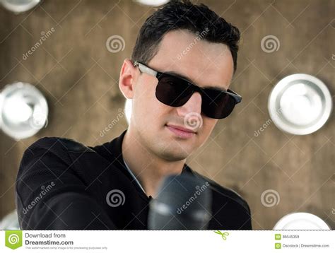 Male Singer In Sunglasses With Microphone Performs In Projectors Stock