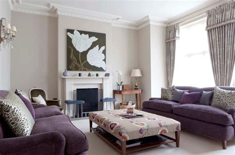 It has hardwood flooring and white framed windows covered in patterned draperies. Living Room With Purple Sofa Furniture