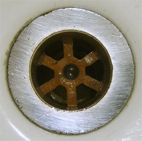 You may be able to hold the pliers with one hand and loosen the nut with the other, or you may need to recruit a helper. Plughole | Plughole of my bathroom sink | James Bowe | Flickr