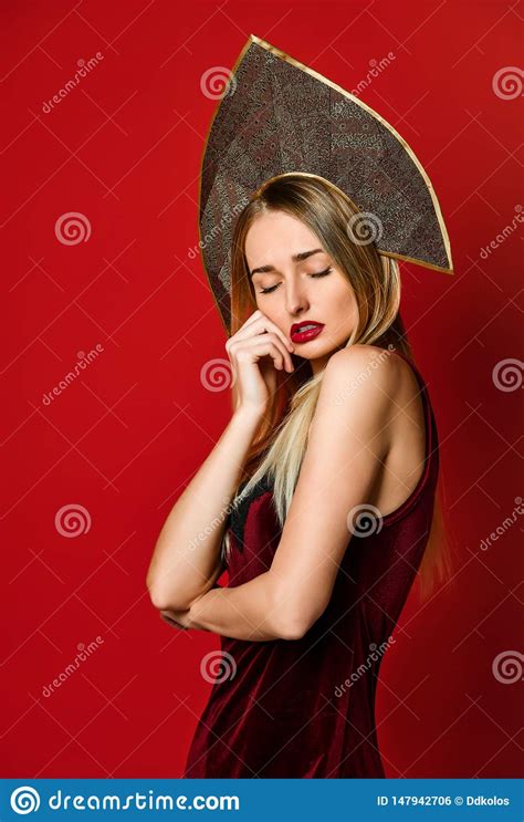 Beautiful Blonde Russian Girl In Traditional Kokoshnik Hat Velvet Festive Dress On A Red
