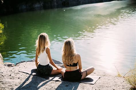 Young Lesbians Couple Exercizing Yoga At Riverside In Sunny Day Stock