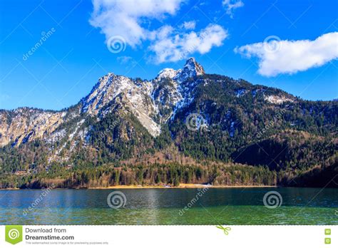 Blue Alpsee Lake In The Green Forest And Beautiful Alps Mountains
