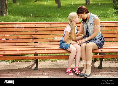 Mom And Daughter Sitting On A Bench In A Park Mother And Child