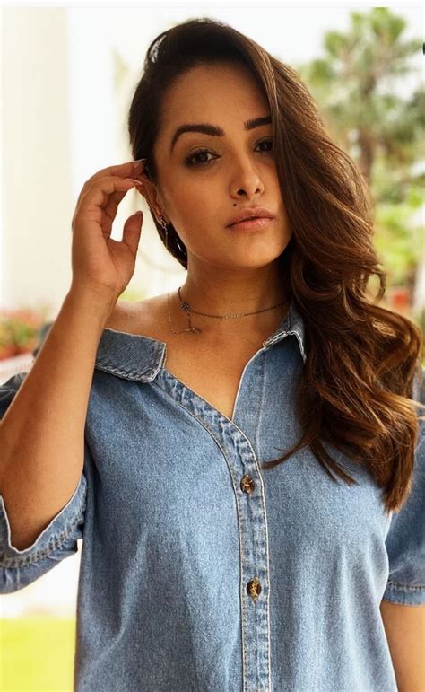 A Woman With Long Hair Wearing A Denim Shirt And Holding Her Hand To