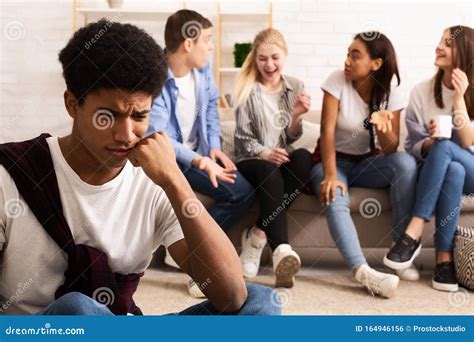 Upset Bullied Guy Sitting Alone Excluded By Bad Friends Stock Photo