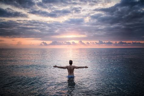 Free Photo Man Stands In The Sea Water Facing Sunset