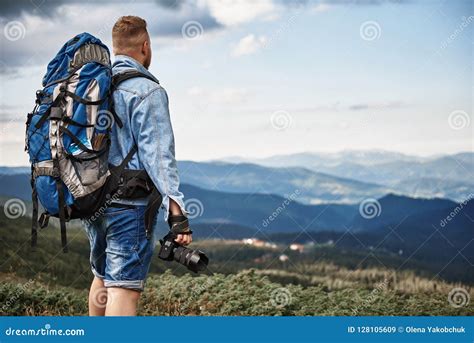 Tall Young Man Carrying Heavy Backpack And Holding His Camera Stock
