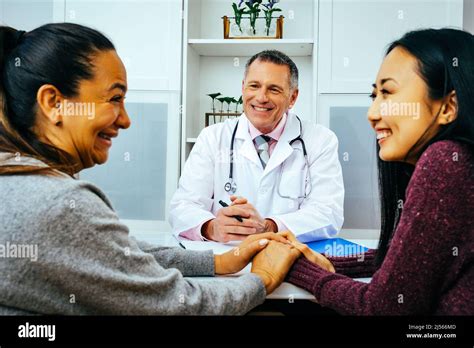 Smiling Doctor And Happy Adult Female Patients In Doctors Office