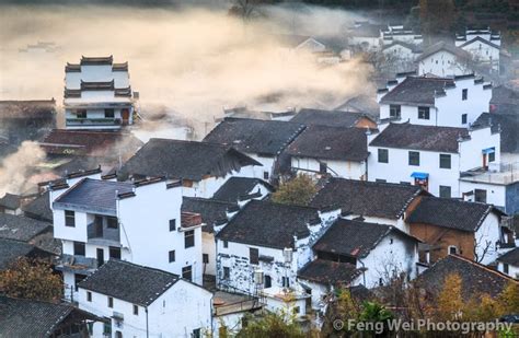 An Aerial View Of A Village In The Mountains With Mist Coming From The