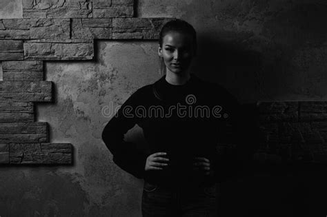 Portrait Of Pretty Young Woman Standing Against Brick Wall Stock Photo