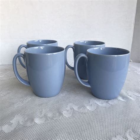 Three Blue Coffee Mugs Sitting On Top Of A White Tablecloth Covered